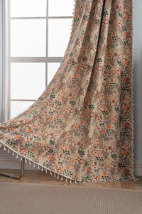 Close-up of bohemian floral curtains with vibrant botanical prints and white cotton tassels