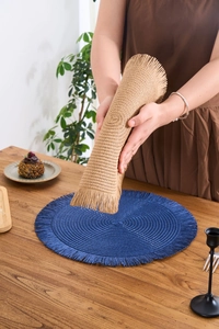 Detailed view of flexible woven round placemat with tassels in blue and natural wood tones