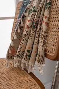 Close-up of bohemian maple leaf jacquard textile with fine fringe tassels on a rattan chair