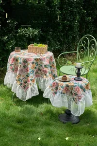 Detailed close-up of floral jacquard tablecloth with elegant white lace ruffle edges