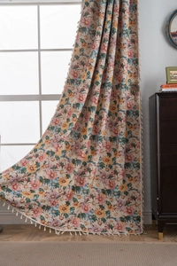 Detailed texture of floral jacquard curtain with white fringe tassels in home setting