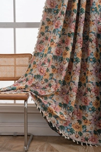 Detail showing colorful daisy floral patterns with white fringe tassels on thick woven fabric