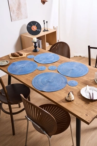 Eight-piece blue woven placemat set with large mats and coasters on wooden table