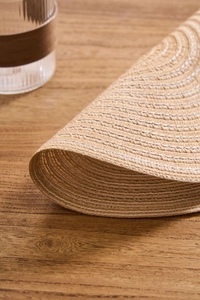 Close-up of Nordic woven round placemat showing beige spiral cotton fiber textures