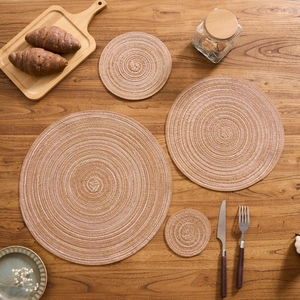 Close-up of woven round cotton placemats with brown and white spiral textures on wood table