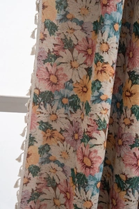 Detail of floral jacquard curtain fabric with colorful daisies and beige tassels