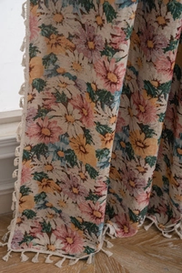 Close-up of floral jacquard fabric with elegant fringe tassels for home decor