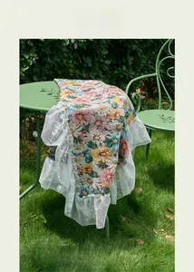 Detail of floral jacquard tablecloth with elegant white lace border in garden setting