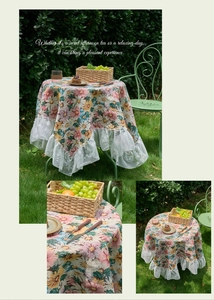Detailed close-up of pink floral tablecloth featuring white lace edges on outdoor grass