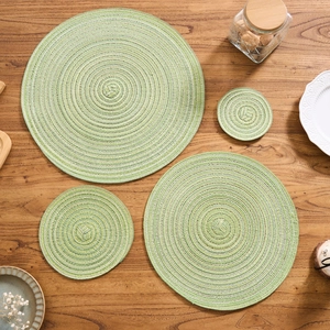 Close-up of woven round placemats with green and white spiral texture on wooden table