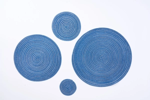 Close-up of four round braided placemats in indigo blue cotton with spiral textures