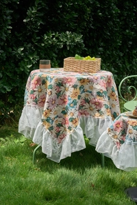 Close-up of floral print tablecloth featuring delicate white lace edge in outdoor setting