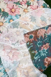 Close-up of pink floral jacquard fabric with delicate white lace trim on grass background