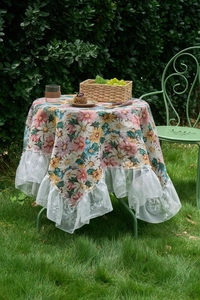 Close-up of floral jacquard fabric with delicate white lace border on a round tablecloth