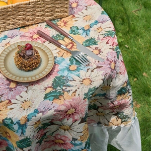 Pink floral jacquard tablecloth with white lace edges on grass for outdoor dining