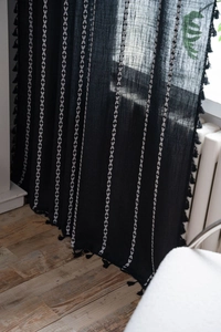 Detail of Nordic style black fabric curtain with white V-embroidery and black tassels