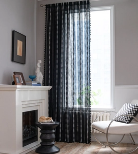Détail d'un rideau noir semi-transparent avec motifs géométriques blancs et franges