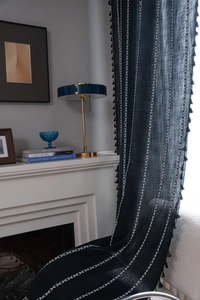 Detail of linen curtains featuring white geometric embroidery and delicate side tassels