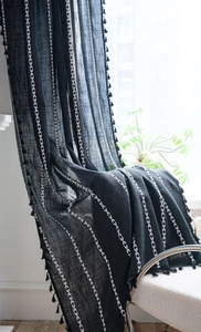 Detail of black semi-sheer curtain with white V-shape embroidery and tassel trim