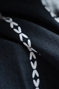 Detailed macro view of white leaf embroidery on premium black Nordic fabric curtains
