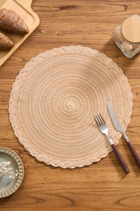 Macro detail of the braided cotton placemat with elegant wavy edges on a wooden table