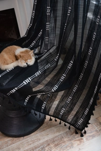 Détail d'un rideau boho noir avec broderies, franges et chat décoratif pour la maison