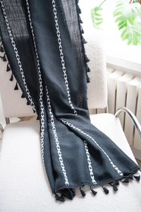 Close-up of black linen curtain featuring white geometric embroidery and small tassel fringe