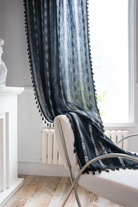 Détail d'un rideau bohème noir et blanc avec broderie géométrique verticale et pompons