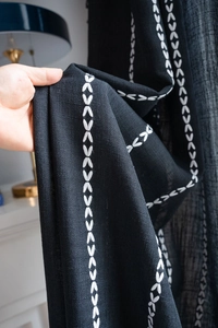 Detailed close-up of Nordic black curtains featuring elegant white geometric embroidery patterns