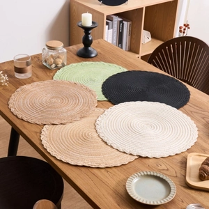 Set of woven round placemats with scalloped edges in natural cotton fibers on a table