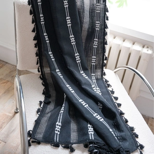 Rideau noir moderne avec broderie blanche et franges sur une chaise blanche