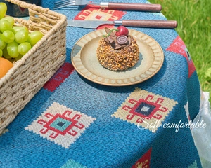 Detail of bohemian blue geometric jacquard tablecloth with thick knit texture on grass