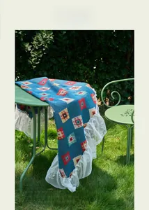 Detail of blue geometric jacquard table runner with delicate white lace trim