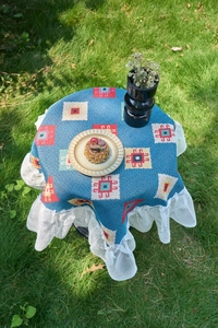 Detail of bohemian blue geometric jacquard tablecloth with white lace edges on grass