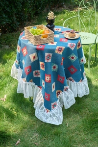 Close-up of bohemian blue geometric tablecloth with white lace edges on outdoor table
