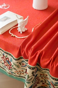 Detailed close-up of red festive jacquard tablecloth with embroidered floral border and lace