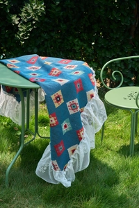Detail of blue geometric woven tablecloth with white lace edges on garden table