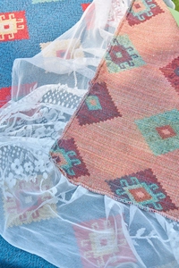 Detail of bohemian geometric weaving with intricate white lace border and thick cotton texture