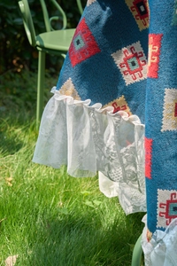 Detail of blue bohemian table cloth with geometric patterns and white lace trim
