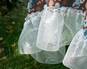 Close-up of vintage red floral jacquard fabric with detailed white lace ruffle edges