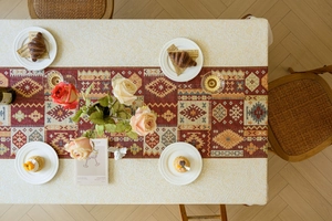 Detail of red geometric bohemian runner on textured cream tablecloth for dining decor