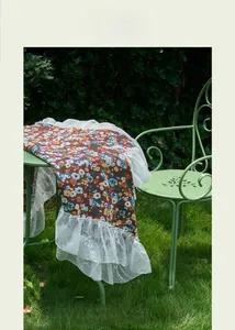 Detail of red floral tablecloth with white lace edges on outdoor green iron furniture