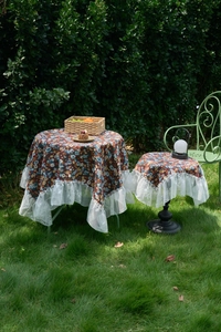 Detail of red floral tablecloth with white lace ruffle edge for outdoor dining
