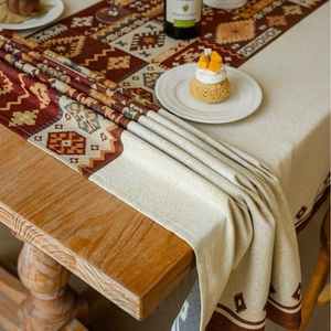 Bohemian jacquard tablecloth with red geometric patterns on a rustic wooden table
