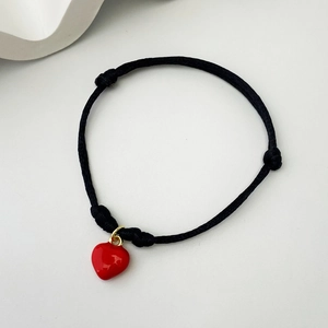 Handmade black woven rope bracelet featuring a glossy red heart charm with gold ring