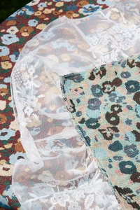 Close-up of vintage red floral jacquard fabric with white lace ruffle edge detail