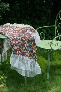 Detail of vintage red floral tablecloth featuring delicate white lace ruffle edges
