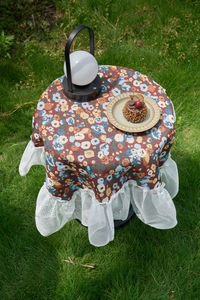 Close-up of vintage floral tablecloth with double-layer white lace trim on garden table