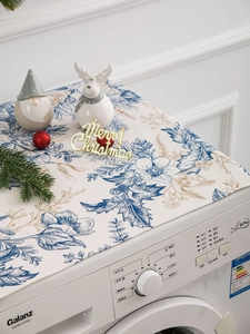 Detailed blue floral pattern dust cover on a front-load washing machine with festive decor