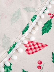 Detailed view of Christmas heart print fabric with soft white pom pom fringe trim